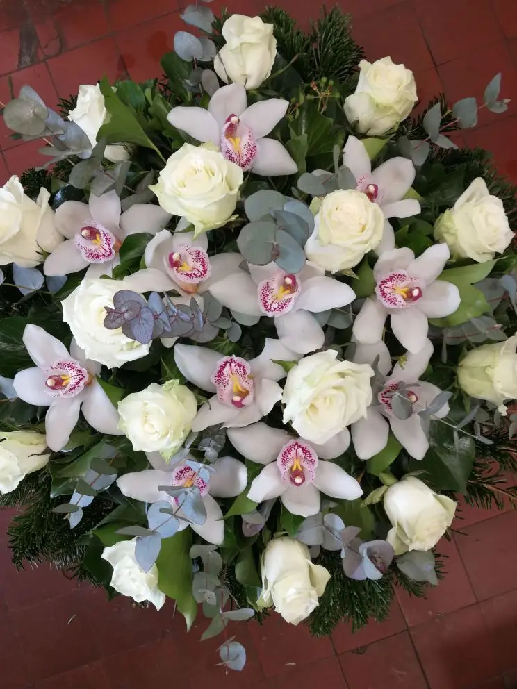Fekvő koszorú fehér rózsával, orchideával és ezüst eukaliptusszal – 60–80 cm. Különleges, modern temetési kompozíció. Nefelejcs Virágüzlet.