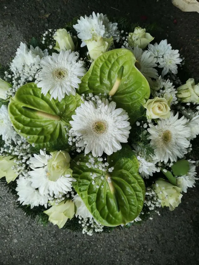 Fekvő koszorú gerbera, rózsa, krizantém, anthurium felhasználásával rezgő díszítéssel. Keresse széles választékunkat üzletemben, vagy rendeljen online!