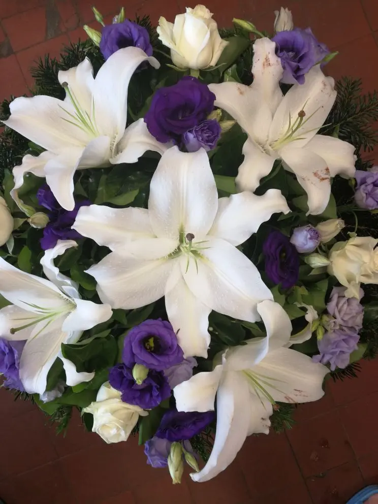 Fekvő koszorú fehér liliommal, fehér rózsával és sötét lila liziantusszal – 60–80 cm. Elegáns, különleges temetési virág. Nefelejcs Virágüzlet.